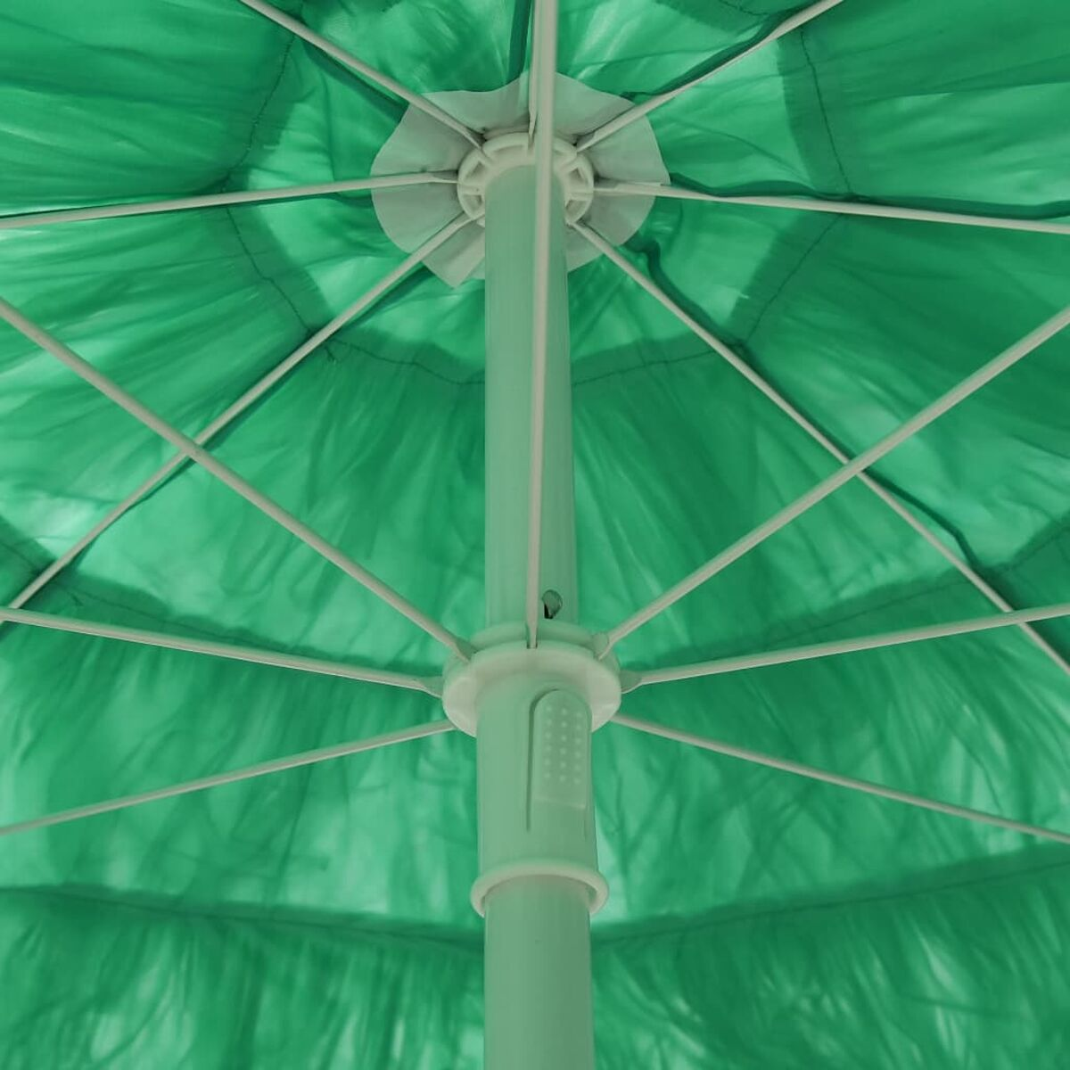 Innenansicht eines grünen Regenschirms mit Rahmen und weißer Stütze, vor weißem Hintergrund.