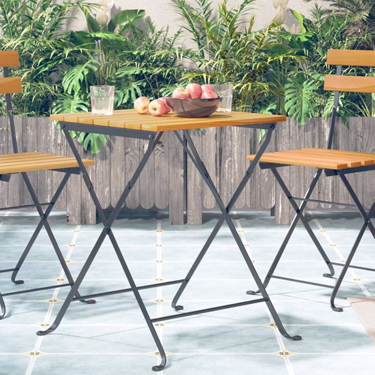 Ein kleines Outdoor-Tisch- und Stuhlsset mit Obst, Gläsern und Holzzaun.