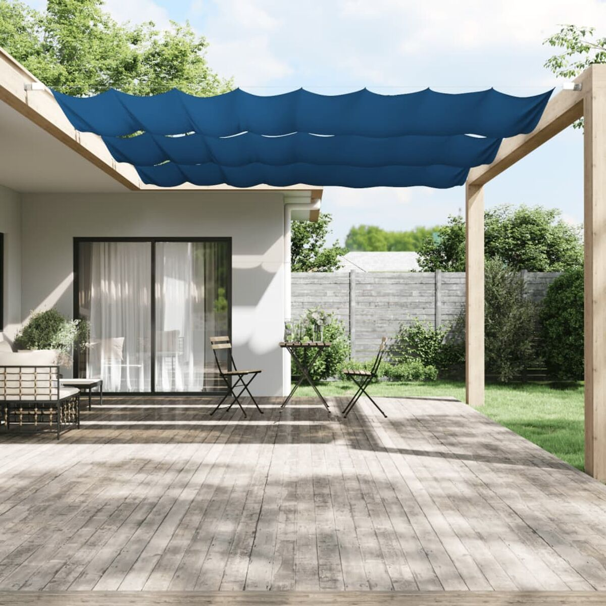 Eine Terrasse mit blauen Sonnensegeln, einem Tisch, Stühlen und einem Haus im Hintergrund.