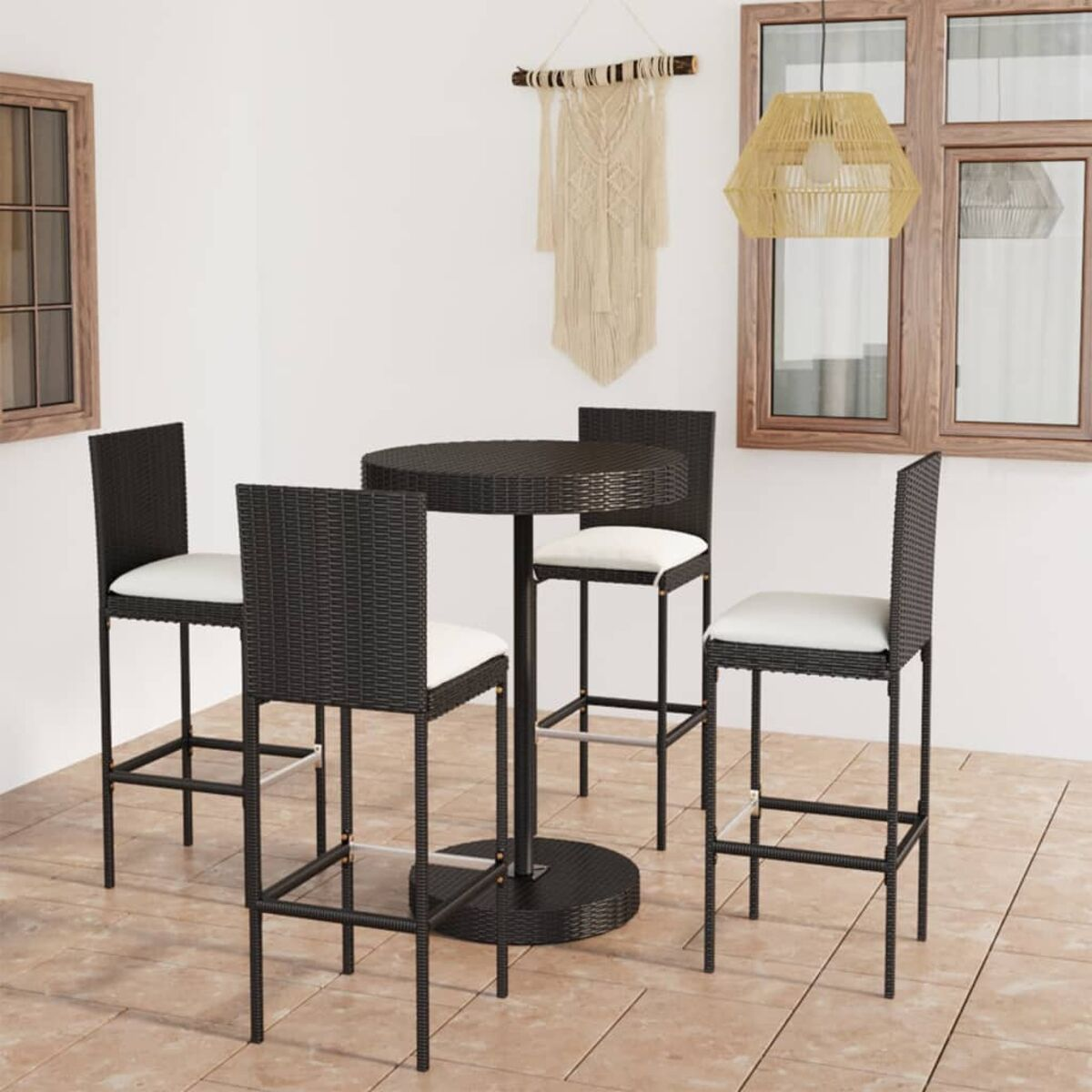 Outdoor-Set mit schwarzen Barhockern und einem runden Tisch, weißen Kissen und Deko.