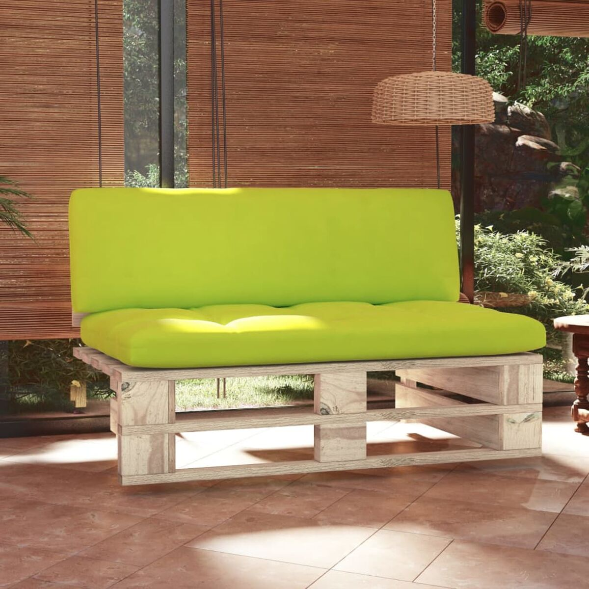 Limettengrünes Kissen auf Palettensofa. Jalousien und Pflanzen im Hintergrund.