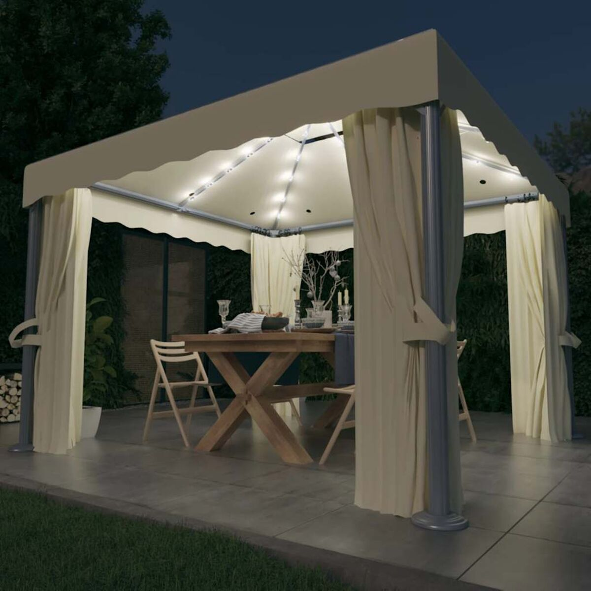 Gartenpavillon bei Nacht. Er hat Vorhänge, Lichter und einen Tisch, der zum Abendessen gedeckt ist. Bäume im Hintergrund.