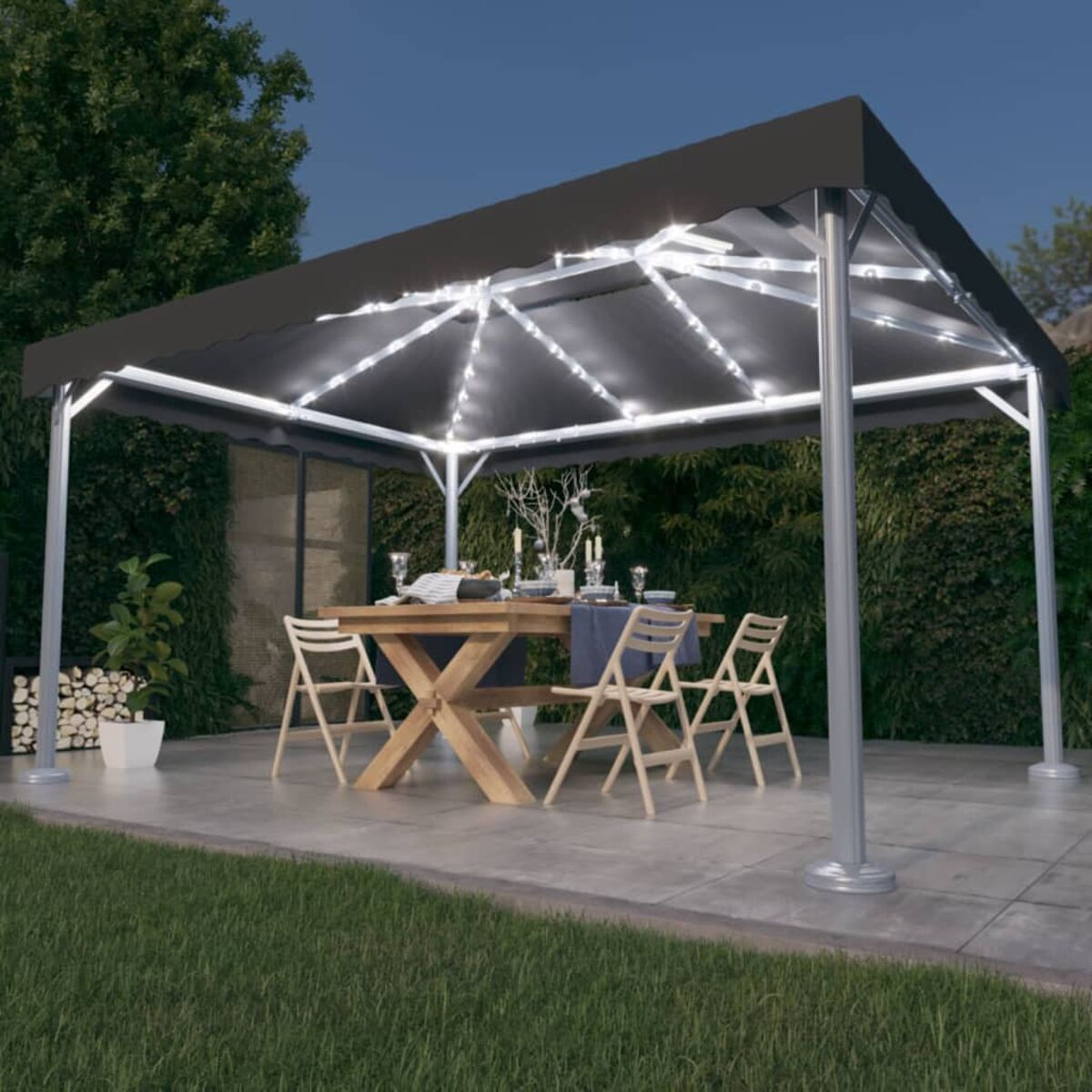 Pavillon bei Nacht, mit Lichtern. Tisch mit Geschirr und Stühlen. Grün im Hintergrund.