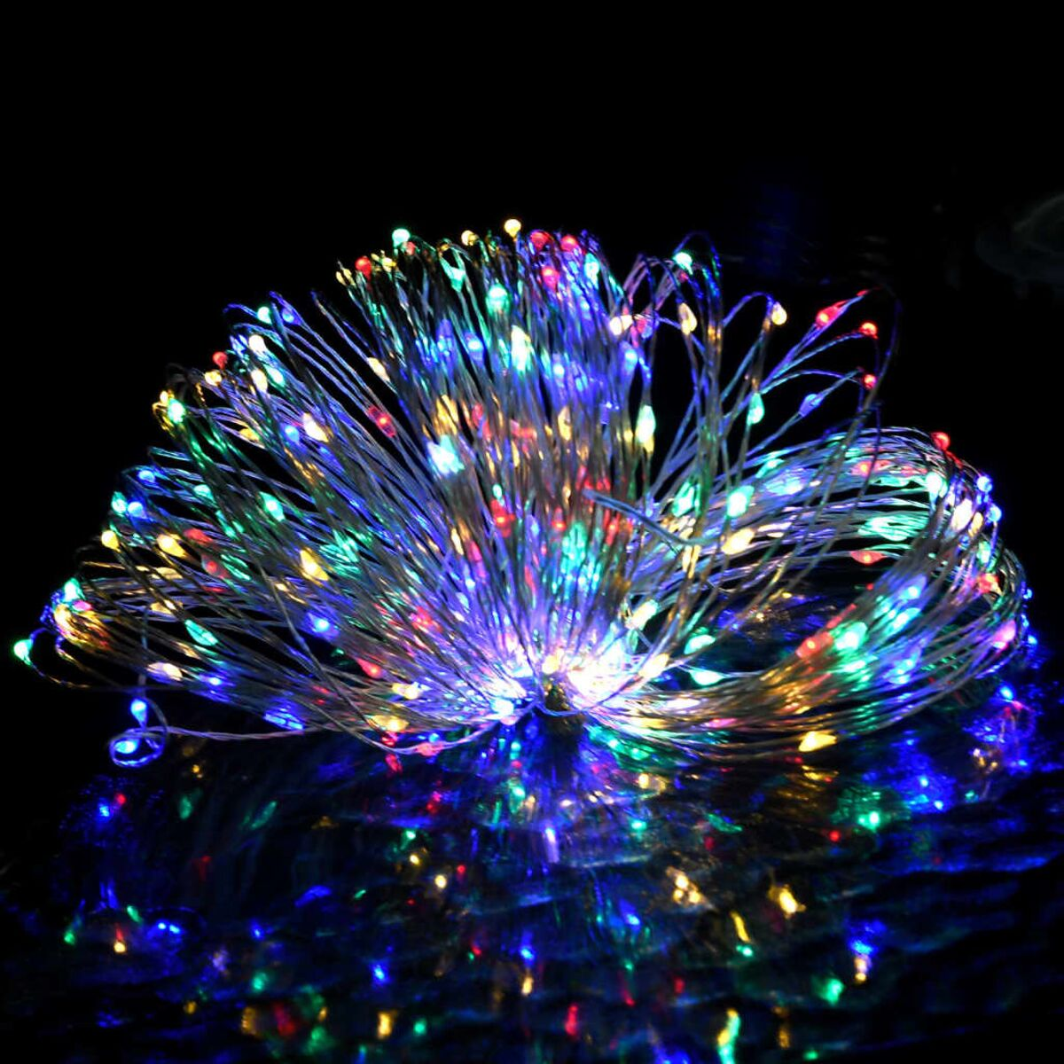 Lichterkette mit mehrfarbigen LEDs, die sich auf einer glänzenden Oberfläche spiegeln.