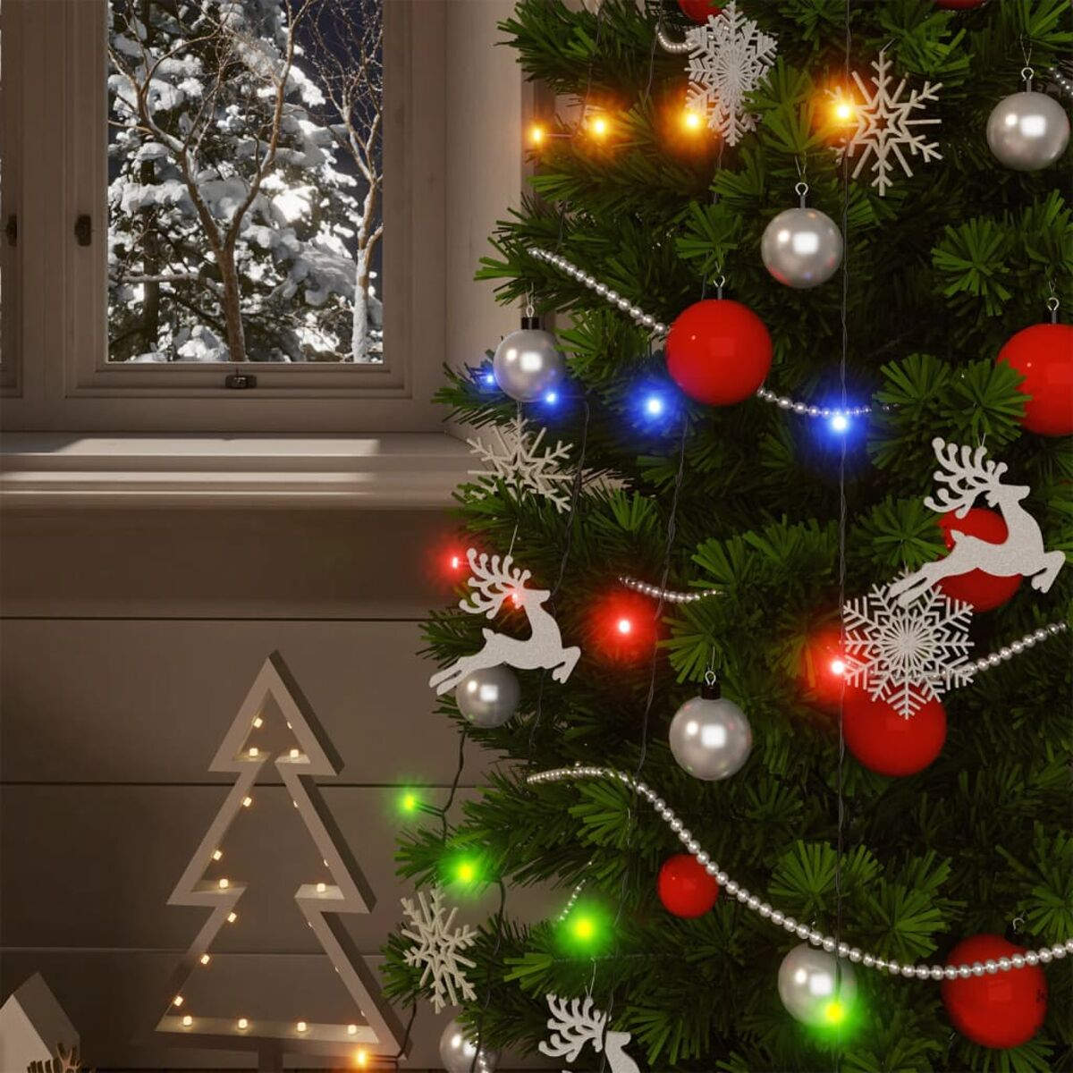 Geschmückter Weihnachtsbaum mit roten und silbernen Ornamenten, Lichtern und Fenster im Hintergrund.