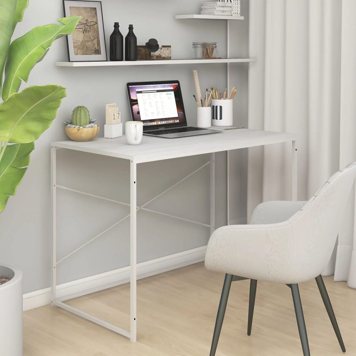 Weißer Schreibtisch mit Laptop, Stuhl und Pflanze vor einer hellgrauen Wand mit Regal.