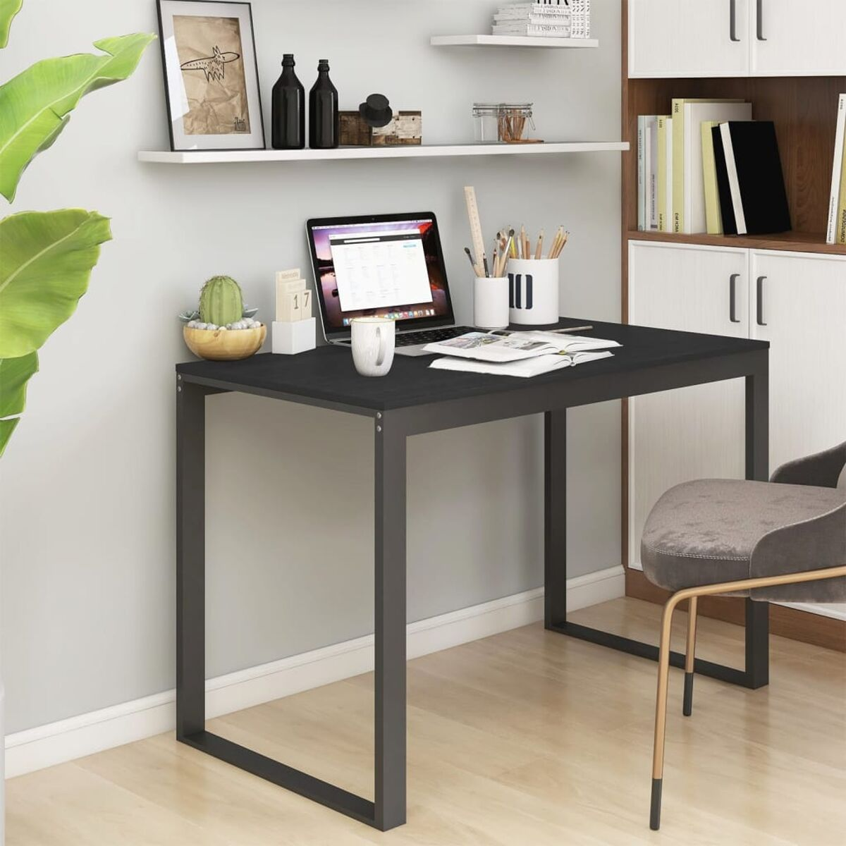 Schwarzer Schreibtisch mit Laptop, Tasse und Bürobedarf. Regale im Hintergrund.