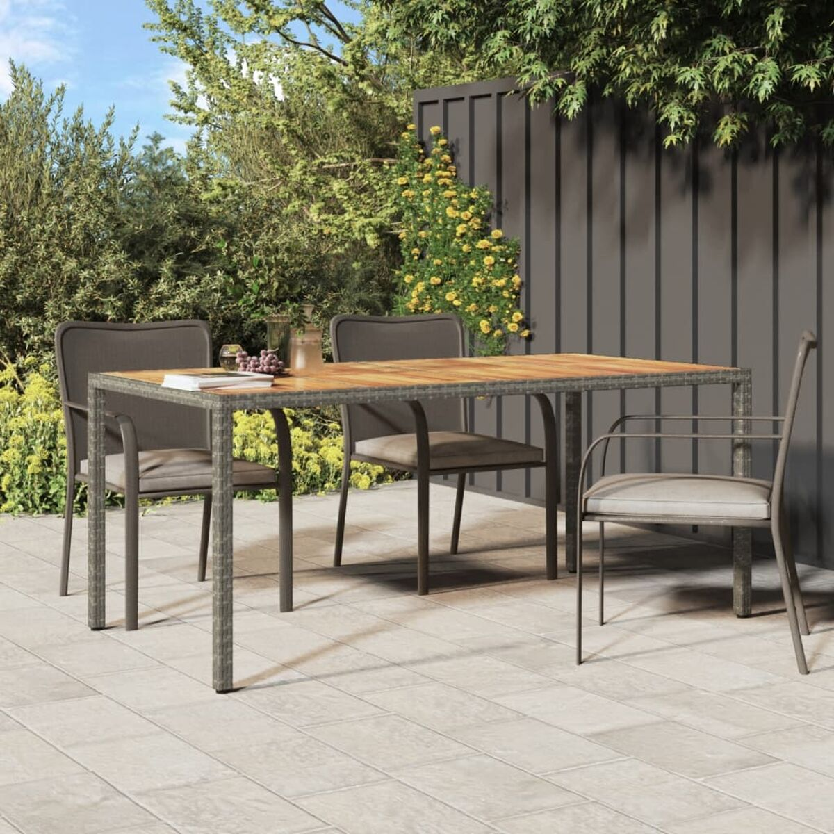 Essgruppe im Freien mit einem Holztisch und Stühlen. Hintergrund ist eine Terrasse und grüne Pflanzen.