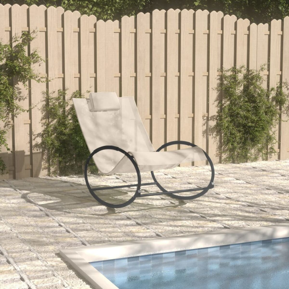 Weißer Schaukelstuhl auf Terrasse am Pool. Grüne Büsche und Holzzaun.