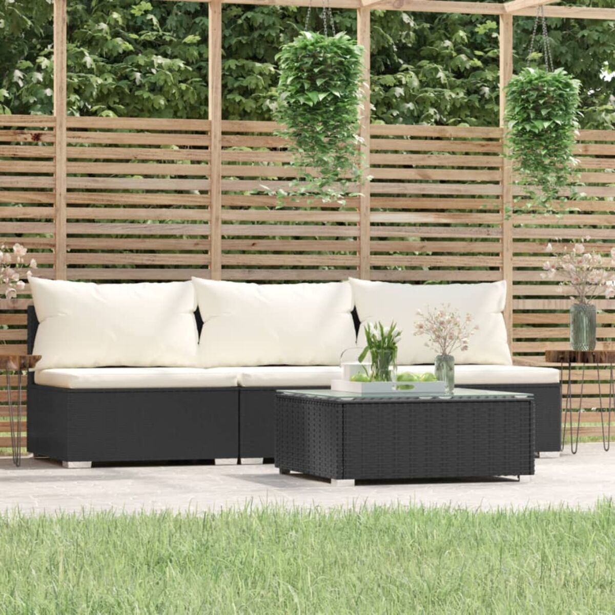 Outdoor-Sitzbereich. Schwarze Korbmöbel, weiße Kissen. Holzzaun im Hintergrund.