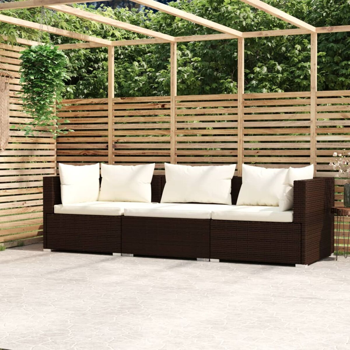 Gewebtes braunes Outdoor-Sofa mit weißen Kissen. Auf einer Steinterrasse, Holzhintergrund.