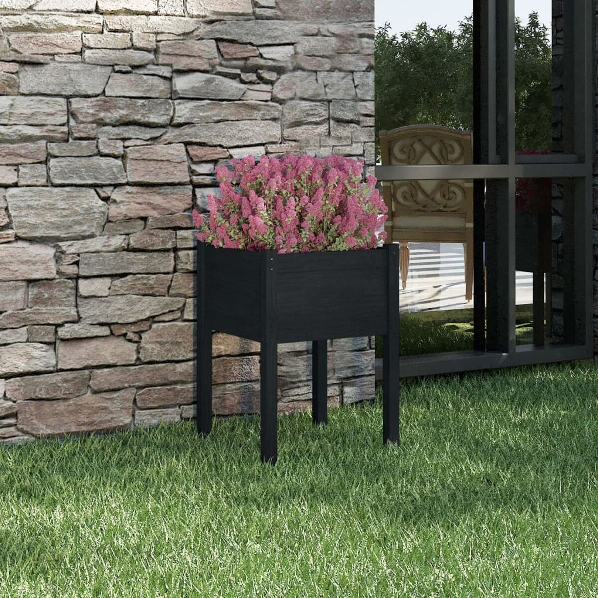 Schwarzer Pflanzkübel mit rosa Blüten vor Steinmauer und grünem Gras.