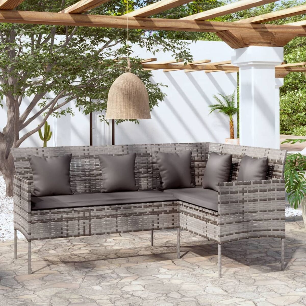 Graues Ecksofa aus Rattan mit Kissen und Hintergrund.