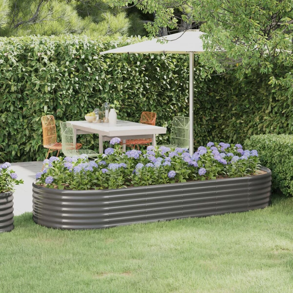 Szene im Freien mit Tisch, Stühlen und Blumenbeet. Grüne Hecke im Hintergrund, weißer Sonnenschirm.
