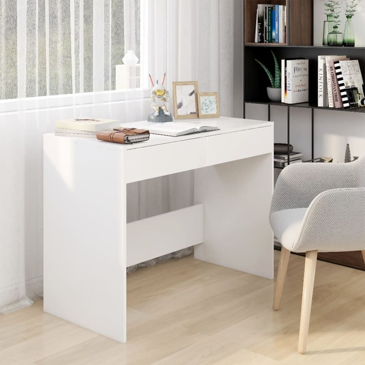Ein weißer Schreibtisch mit Stuhl, Büchern und Dekoration darauf.
