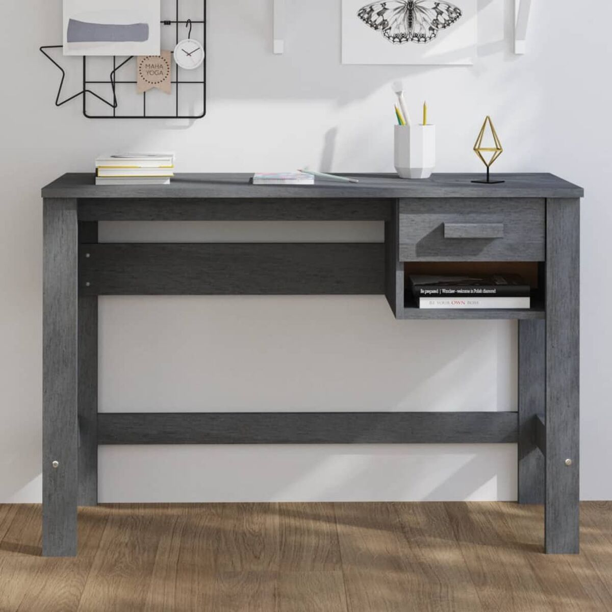 Grauer Holzschreibtisch mit Schublade und kleinem Regal. Bücher, Stifte und Deko sind oben platziert.