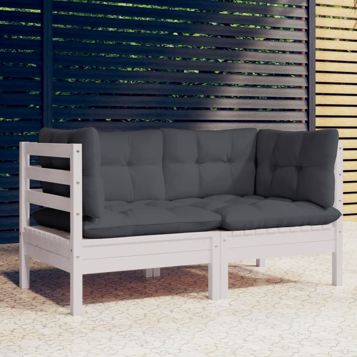 Weißes Holz-Outdoor-Sofa mit dunkelgrauen Kissen. Gemusterter Boden, sonniger Tag.
