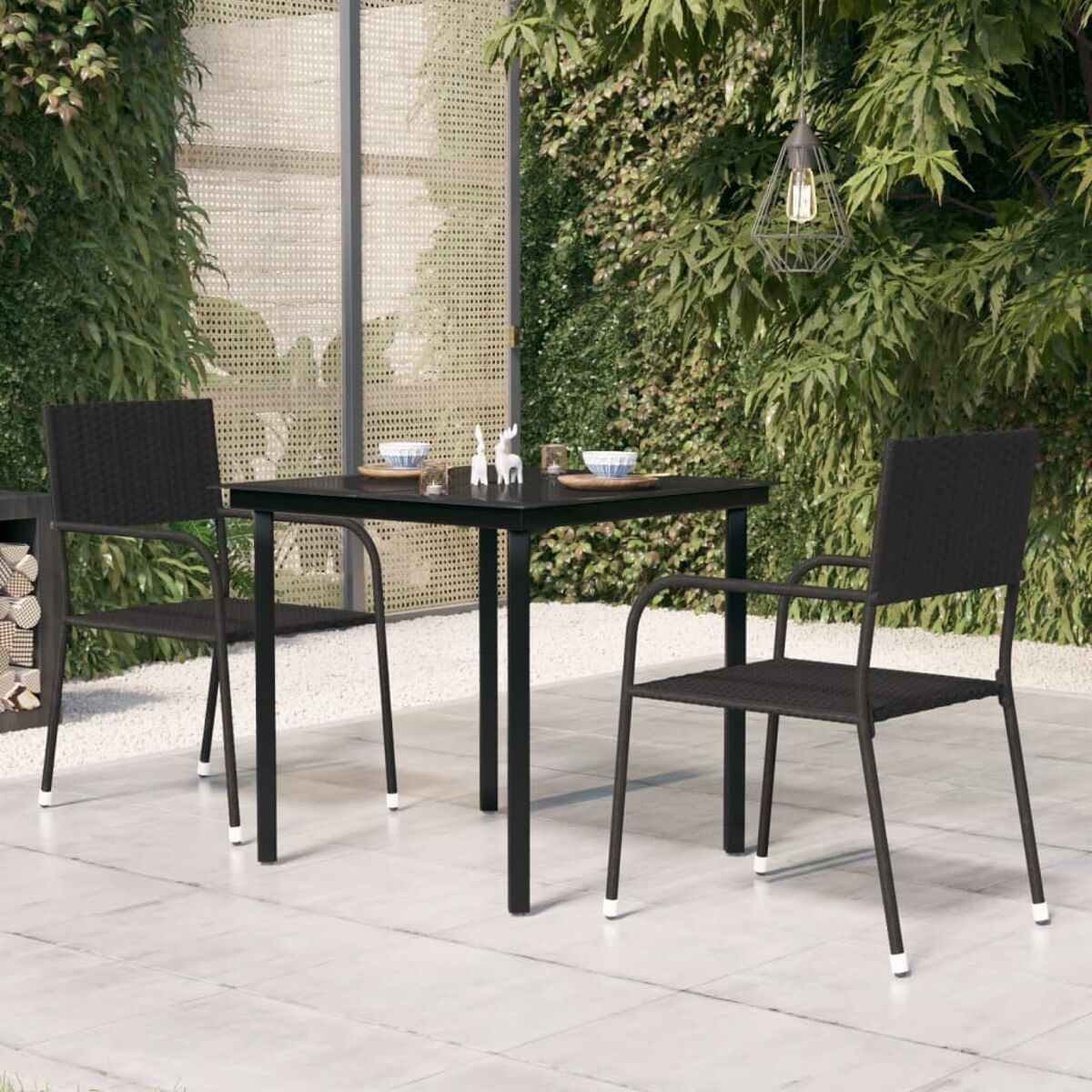 Ein Terrassenset mit einem schwarzen Tisch und zwei Stühlen. Der Hintergrund zeigt Grün.