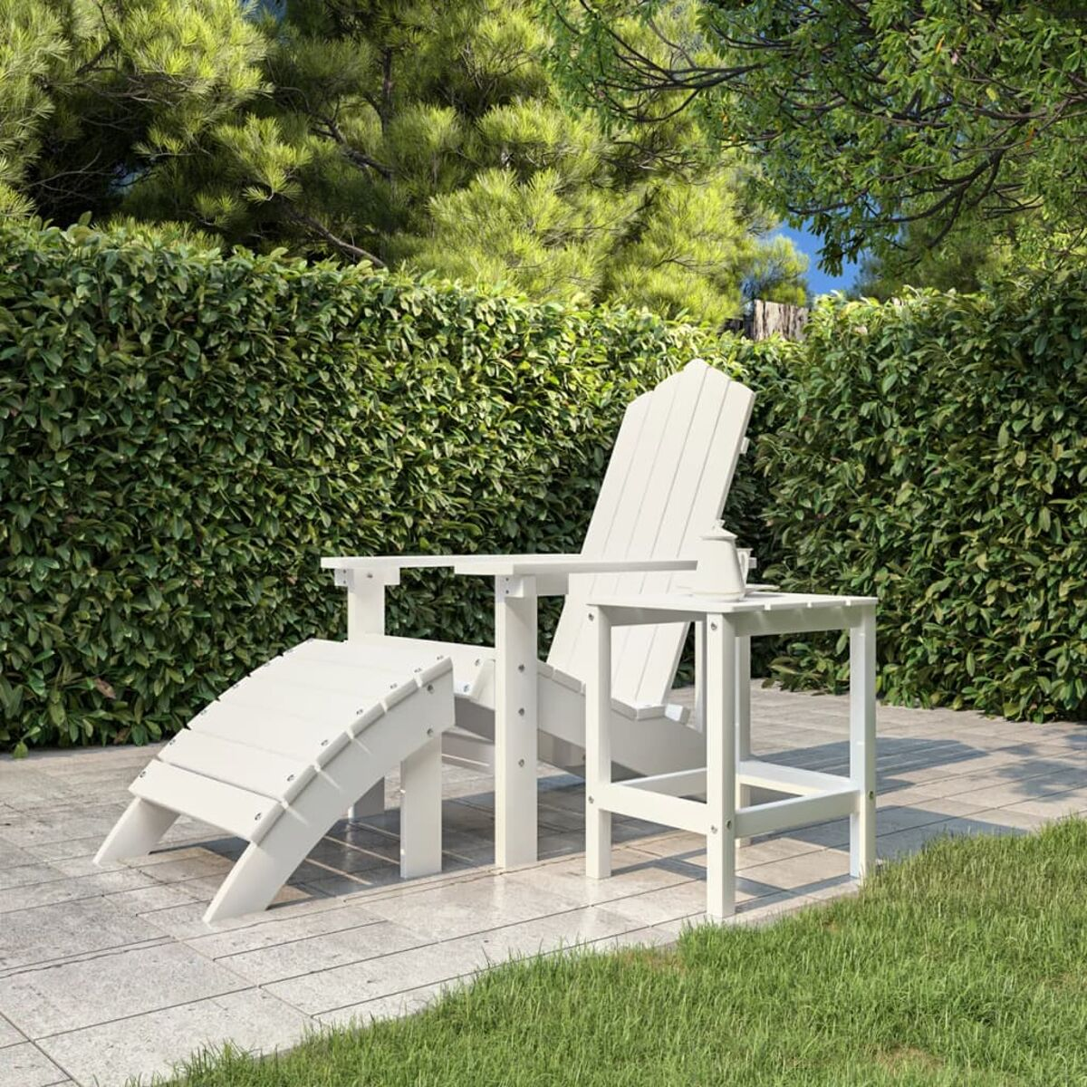 Weißer Adirondack-Stuhl, Fußstütze und kleiner Tisch im Garten.