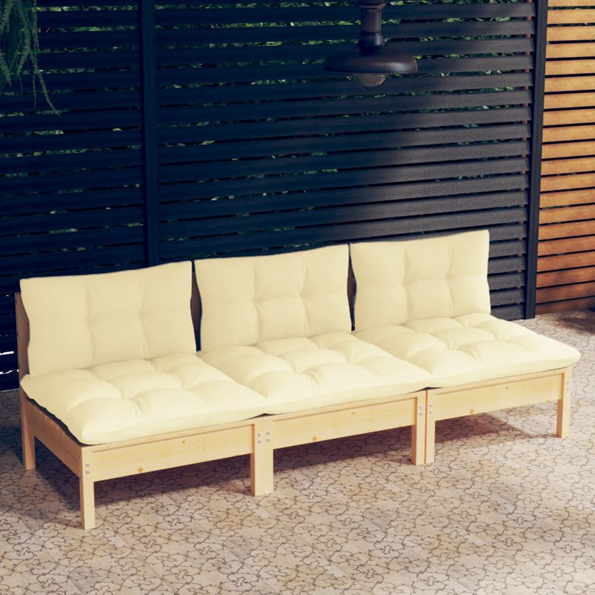 Beiges gepolstertes Outdoor-Sofa auf einer Terrasse, im Hintergrund ein dunkler Holzzaun.