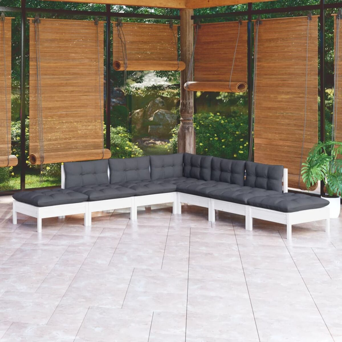 Patio esterno con divani in legno bianco con cuscini grigi. Persiane in bambù e verde.