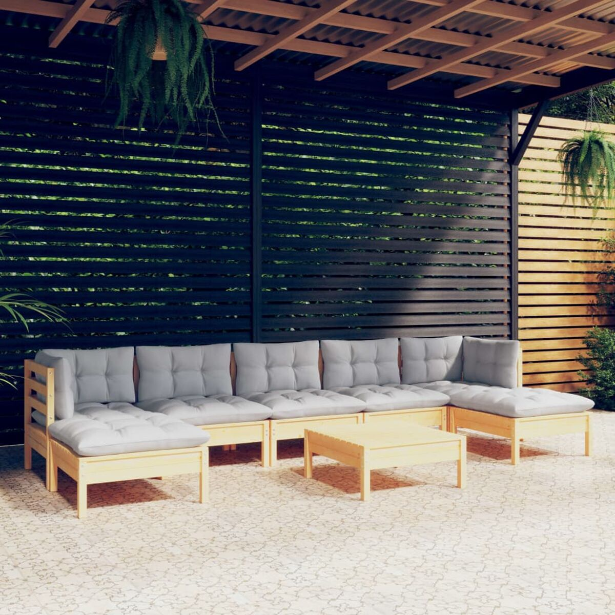 Outdoor-Sofagarnitur mit hellen Kissen. Beinhaltet einen Tisch. Set ist in einem Hof unter Holzstruktur.