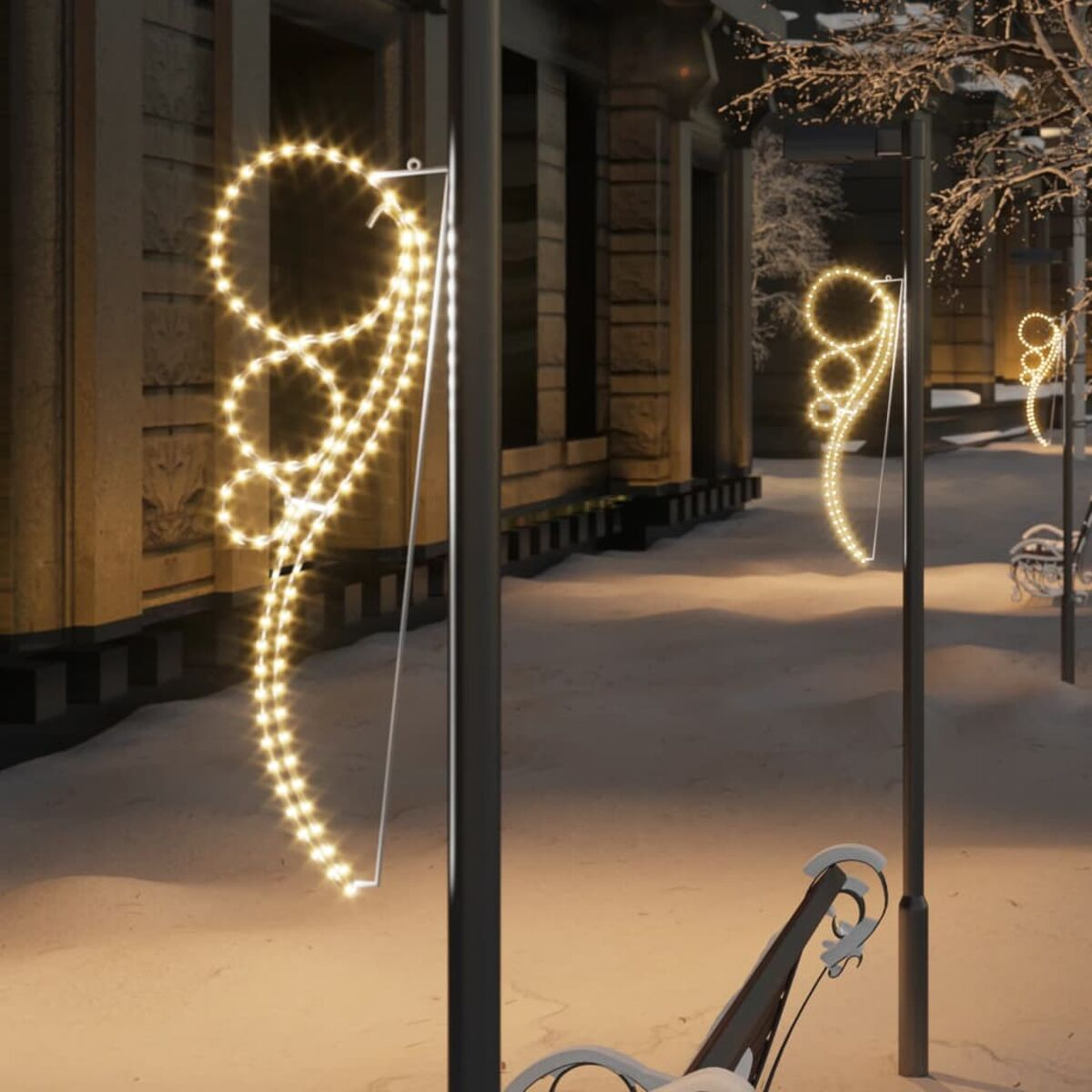 Weihnachtsbeleuchtung im Freien an schwarzen Laternenmasten. Winterszene. Beiges Gebäude im Hintergrund.