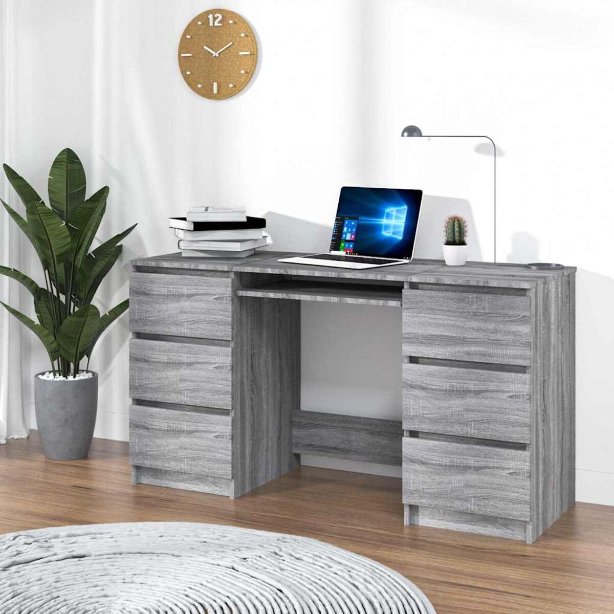 Holzschreibtisch mit Schubladen und Laptop. Eine Uhr und eine Pflanze an der Wand.