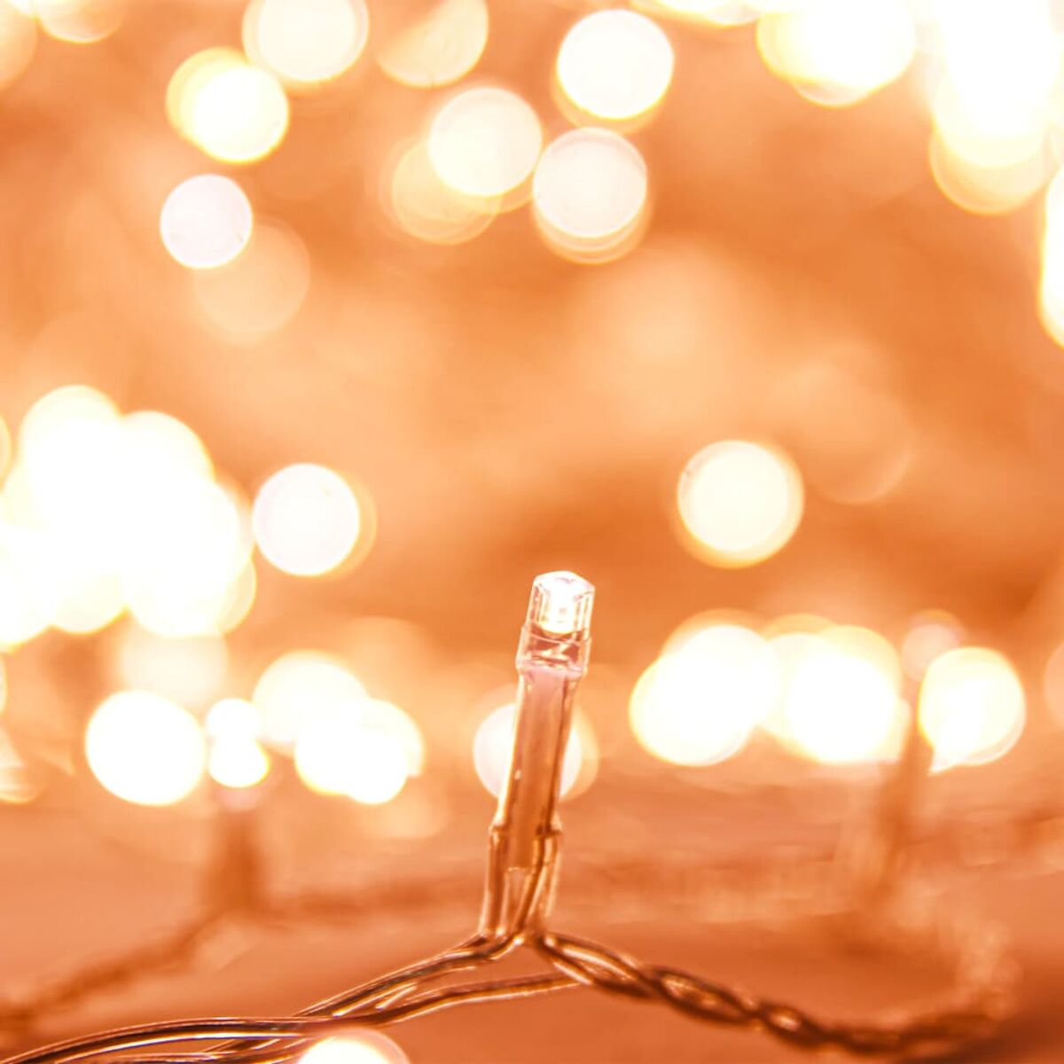 Nahaufnahme einer einzelnen LED-Leuchte einer Lichterkette, mit verschwommenen Lichtern im Hintergrund.