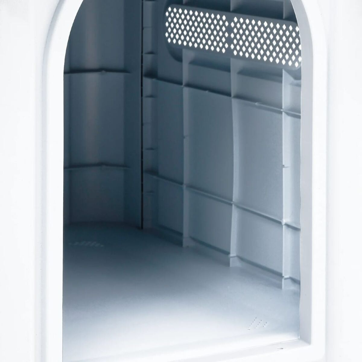 Ein gewölbter Eingang in ein weißes Interieur. Hellblaues Interieur mit gitterartiger Decke.