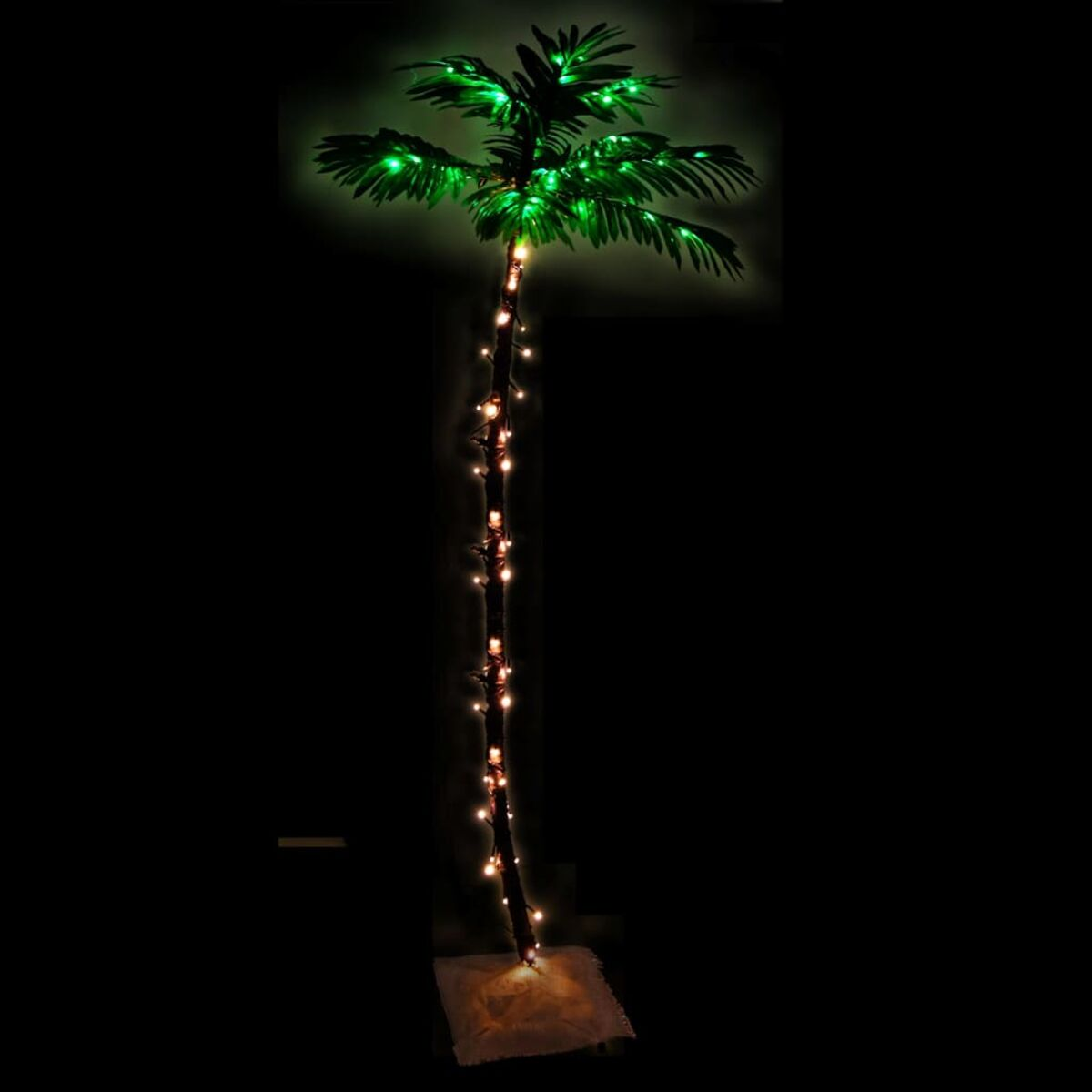 Hohe künstliche Palme mit grünen Blättern und Lichterketten auf schwarzem Hintergrund.