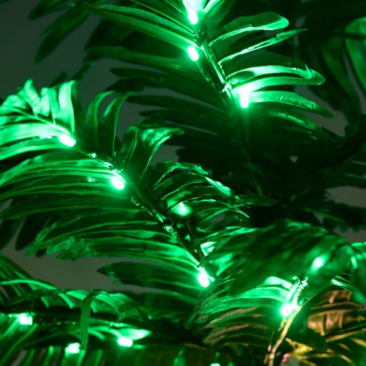Grüne Blätter, beleuchtet von vielen grünen Lichtern. Dunkler Hintergrund.