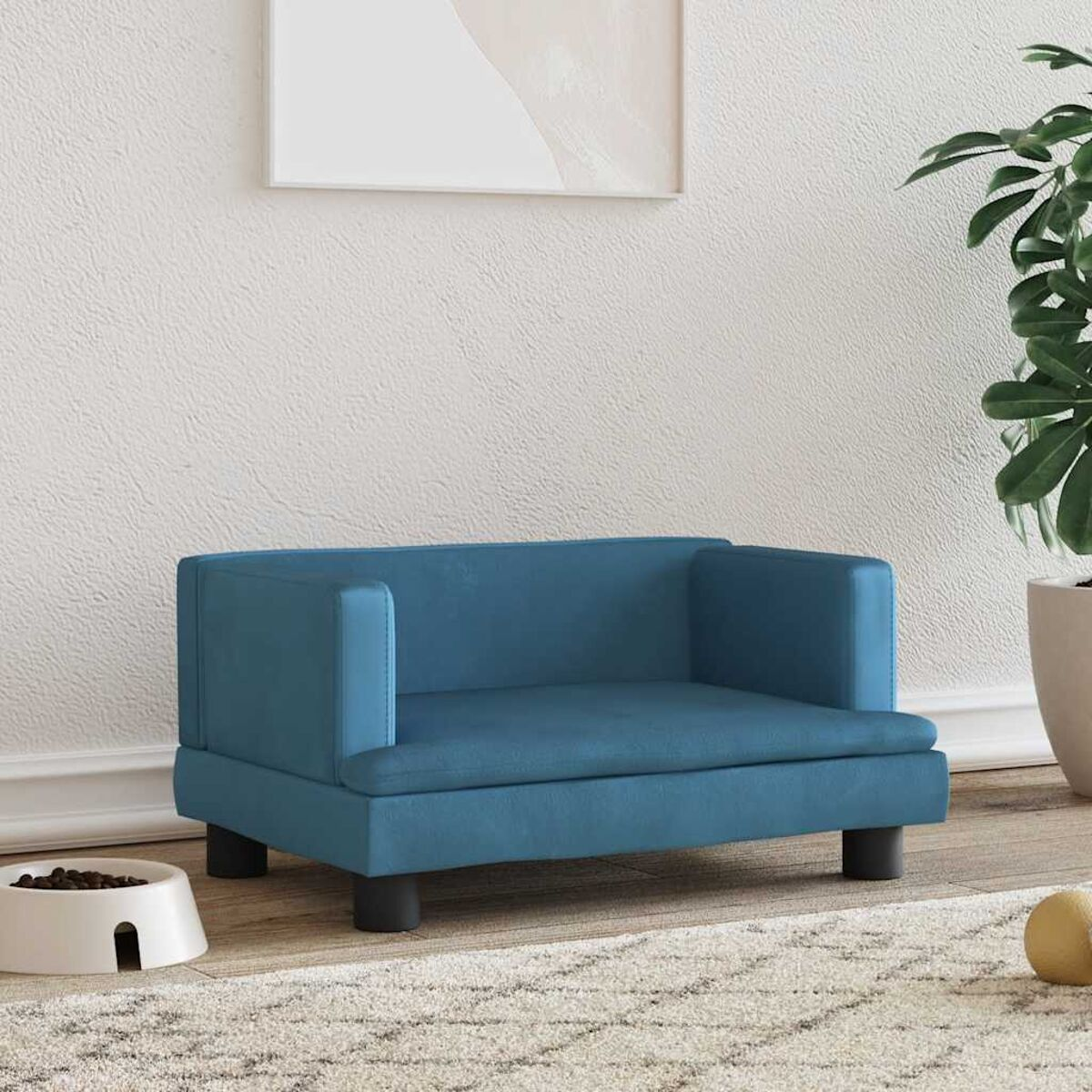 Blaues Haustiersofa auf einem Teppich. Eine weiße Schüssel und ein Spielzeug im Vordergrund.