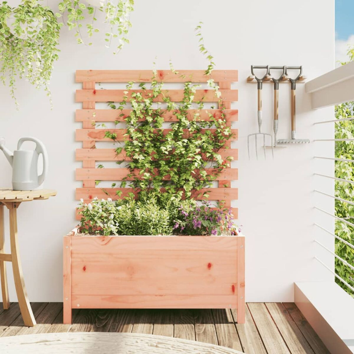 Holz-Pflanzgefäß mit Pflanzen und Holzspalier an weißer Wand. Gartengeräte hängen darüber.