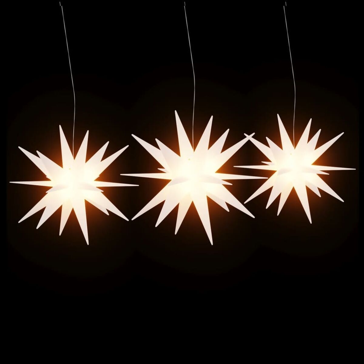 Drei weiße sternförmige Lichter hängen an schwarzen Drähten vor schwarzem Hintergrund.