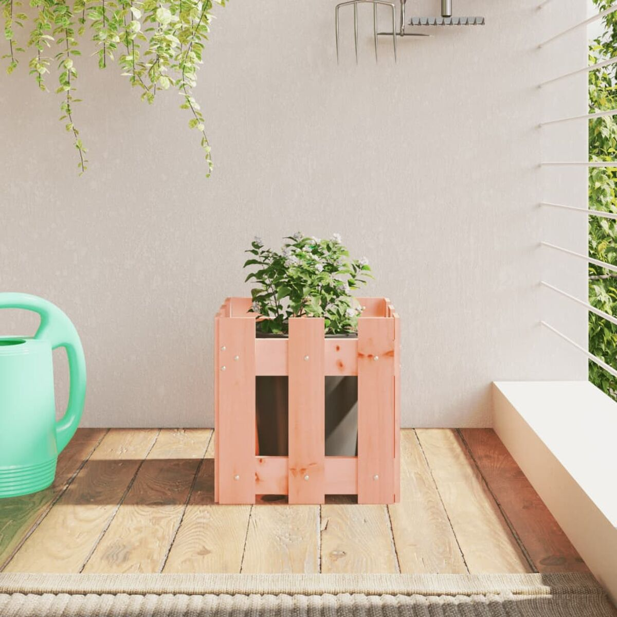 Rosa Holzpflanzer mit Pflanze auf Balkon, grüne Gießkanne links.