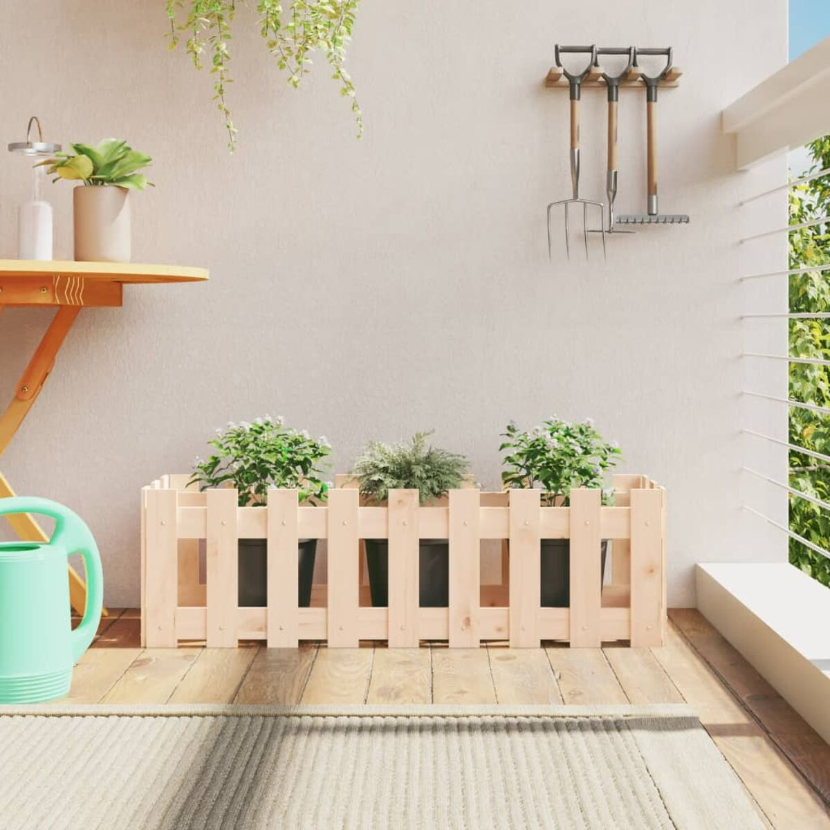 Balkon mit Pflanzen in einem Holzzaun-Pflanzgefäß, Werkzeugen und einer Gießkanne.