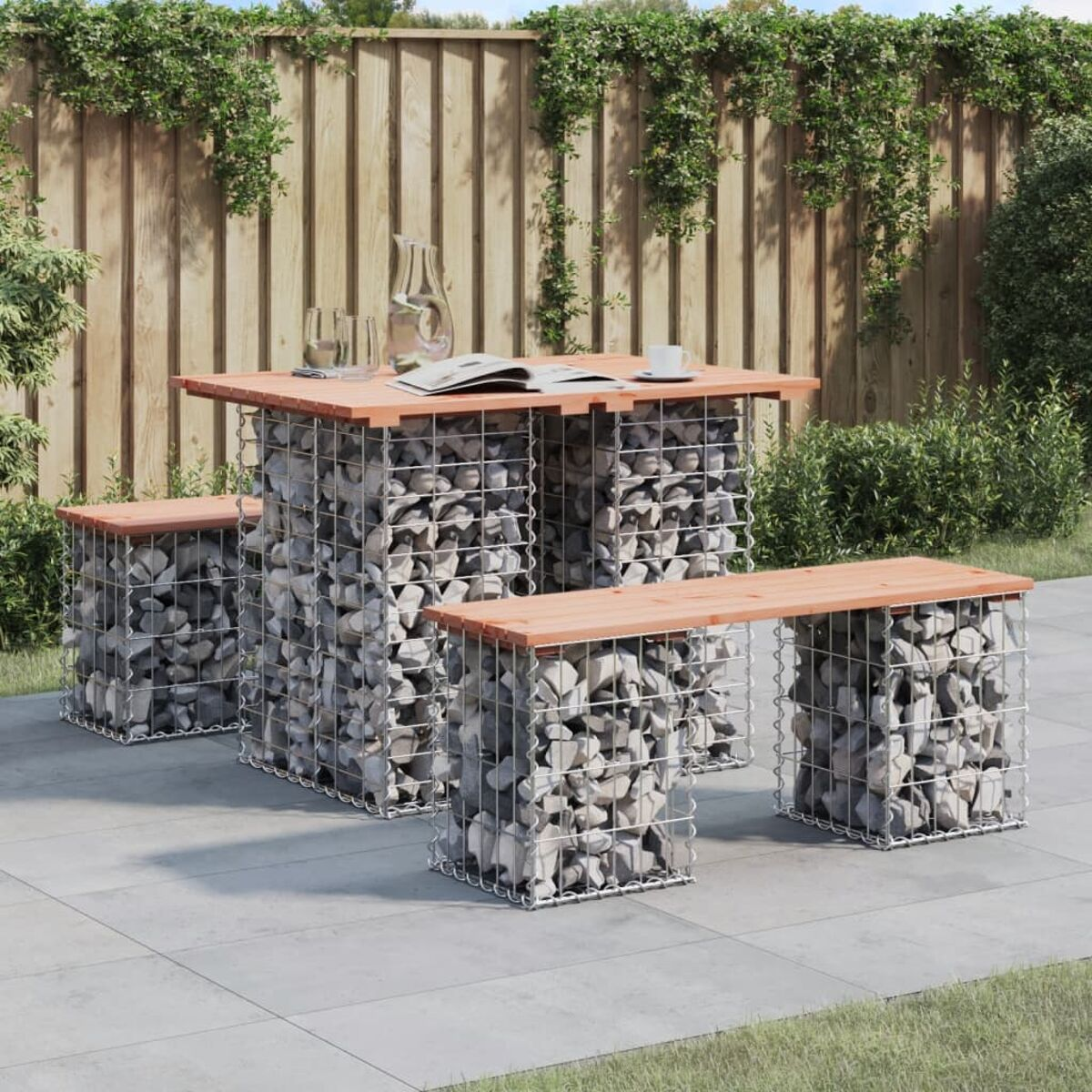 Terrassengarnitur: Tisch und zwei Bänke, alle mit steingefüllten Gabionen und Holzplatten. Hinterhof.
