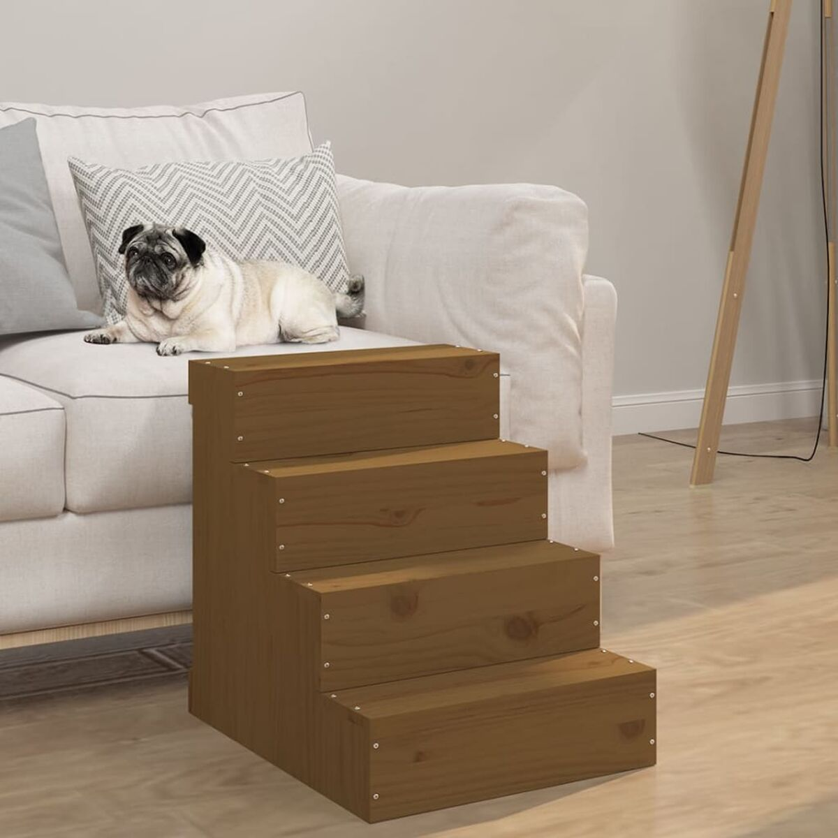 Hölzerne Haustiertreppe neben einem weißen Sofa. Ein Mops liegt auf dem Sofa. Die Treppe ist braun. Die Szene ist drinnen.