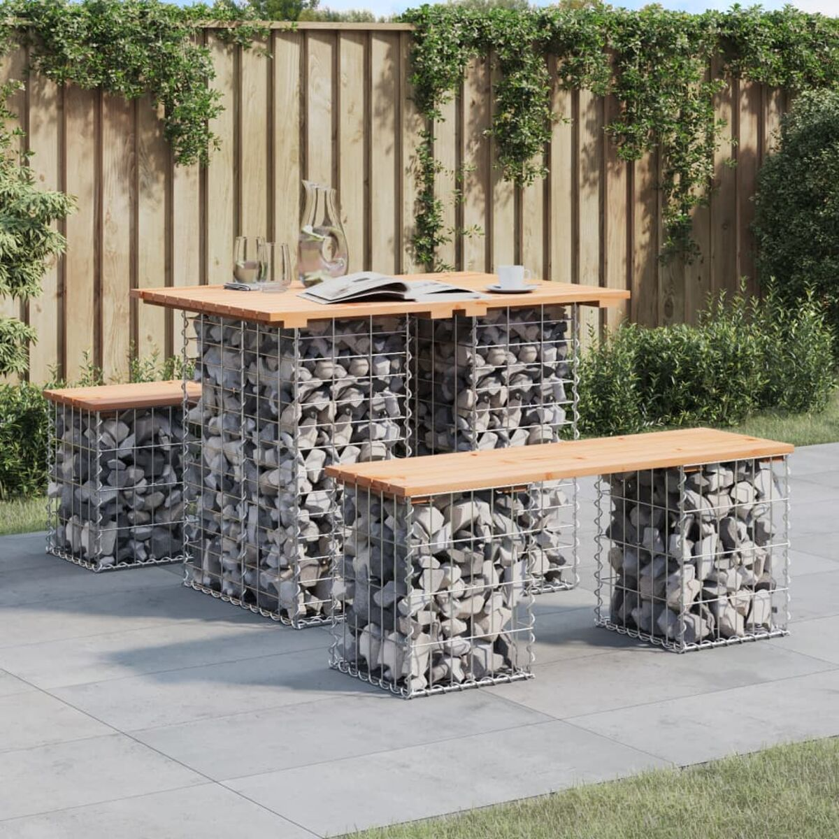 Steintisch und -bänke im Freien. Stein gefüllte Drahtrahmen tragen Holzplatten.