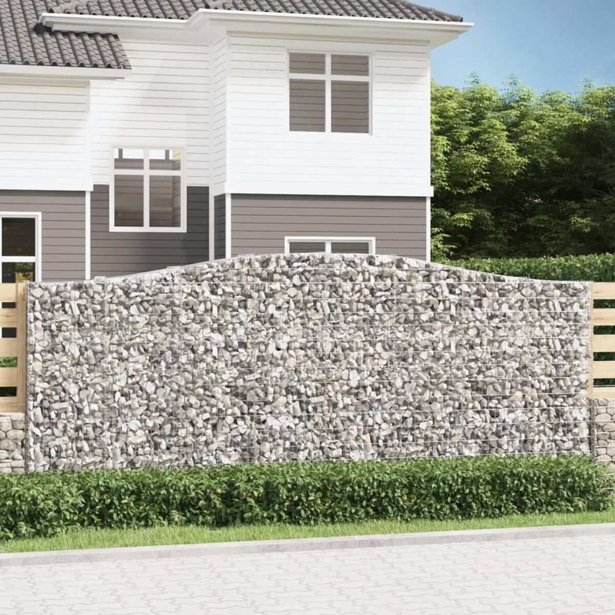 Ein Haus mit einer Gabionenwand davor, zusammen mit einem Holzzaun.