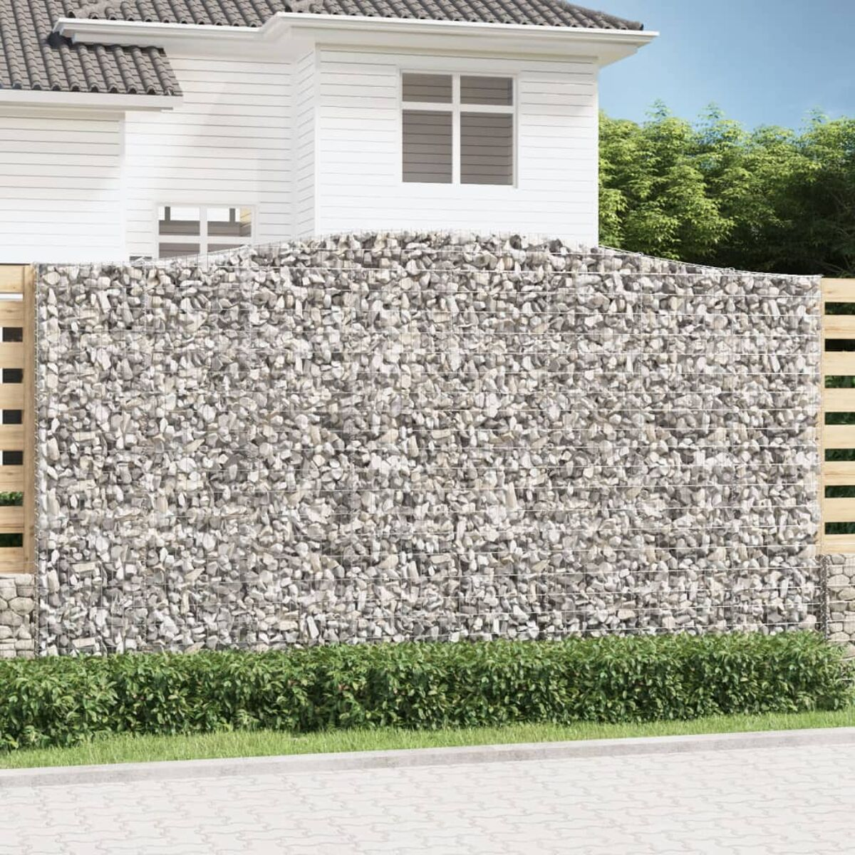 Ein Gabionen-Zaun vor einem Haus. Die Mauer ist mit Steinen gefüllt und hat einen Holzzaun an der Seite.