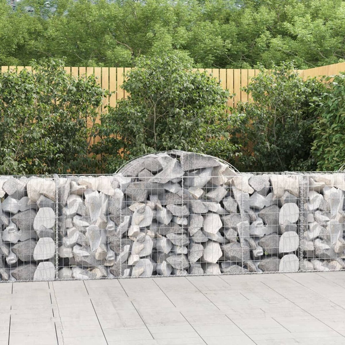 Eine Steinmauer mit Holzzaun und grünen Büschen dahinter. Der Hintergrund ist grün.