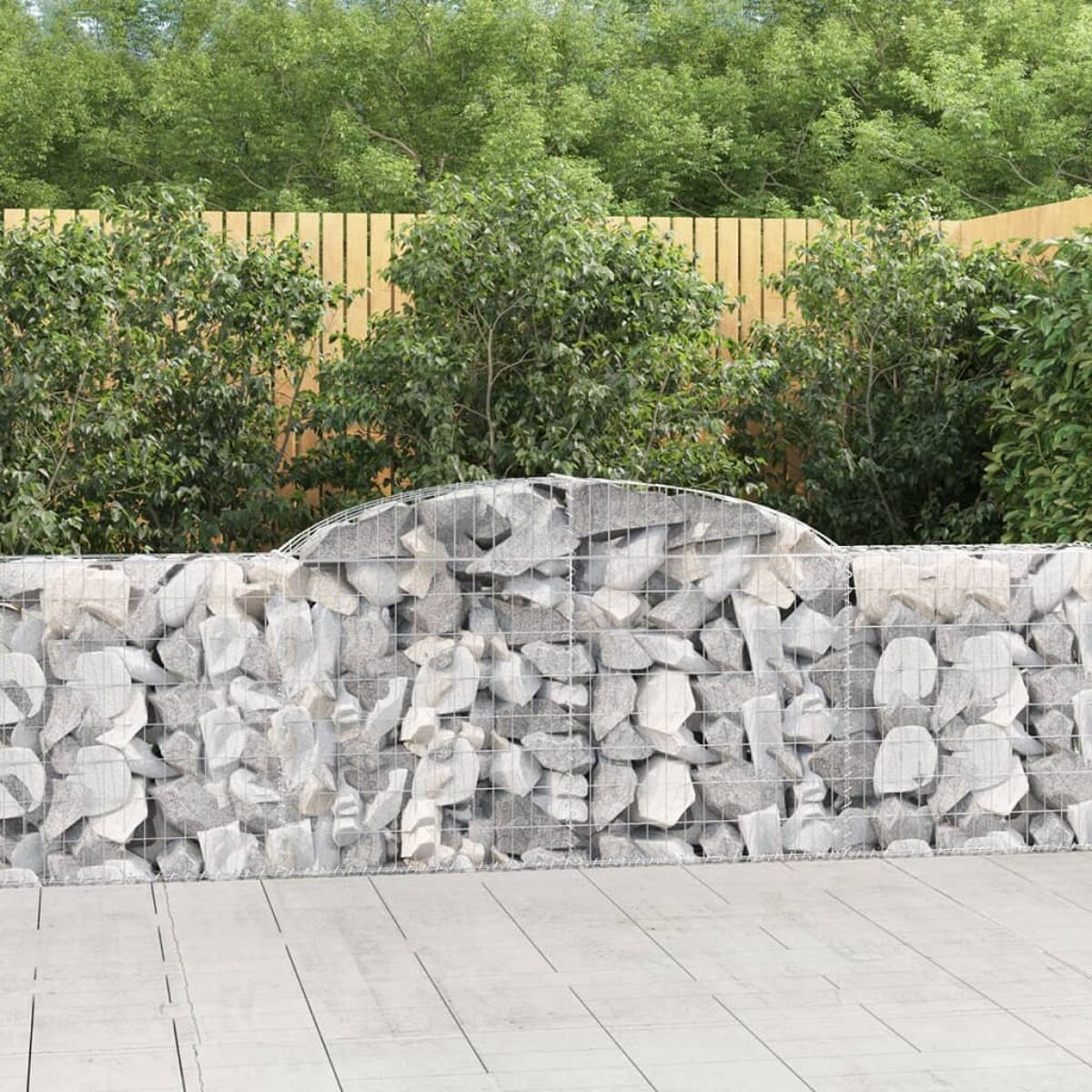 Eine Steinmauer aus Felsen, mit Holzzaun und grünem Hintergrund. Außenszene.
