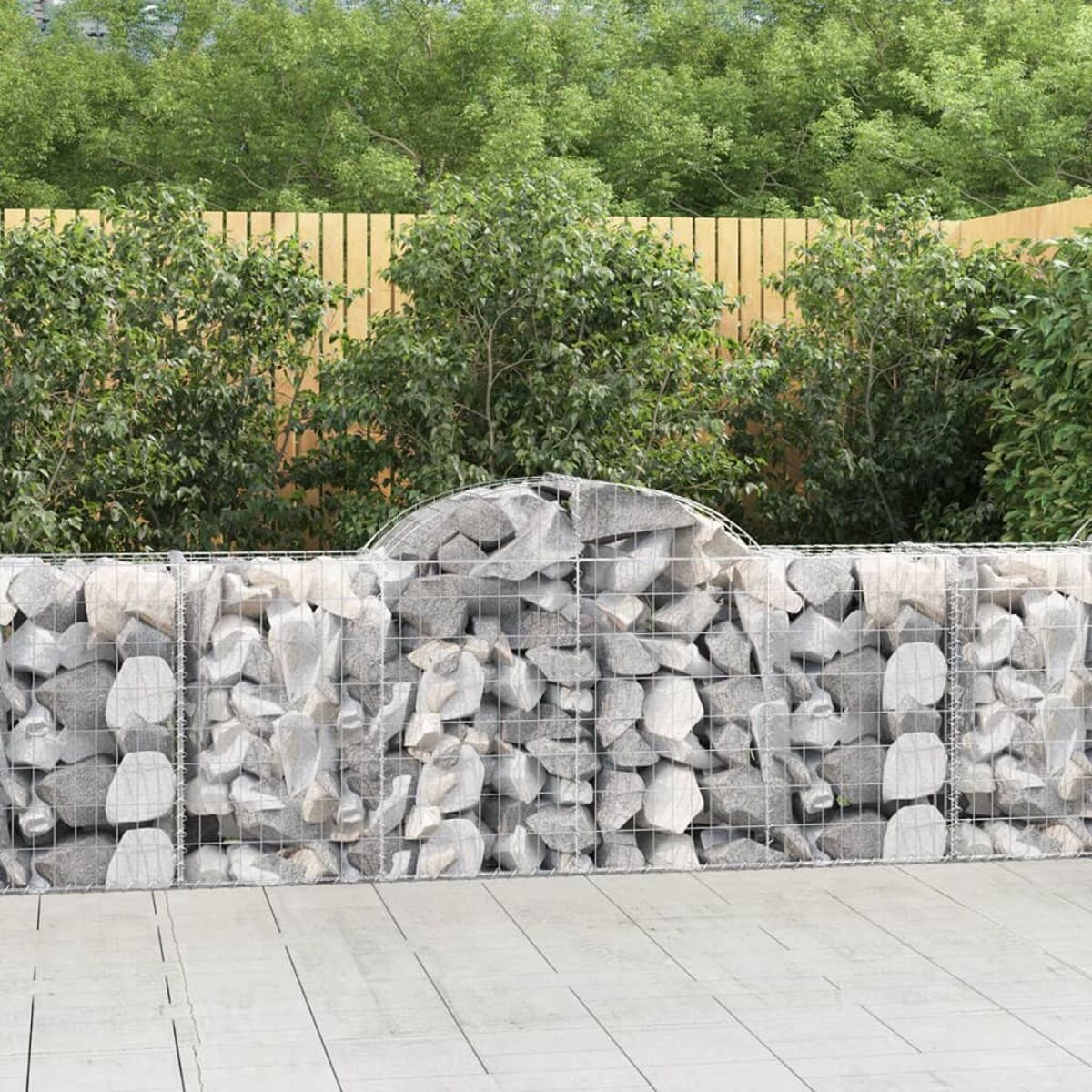 Eine Steinmauer mit Holzzaun und grünen Büschen dahinter. Der Hintergrund ist grün.