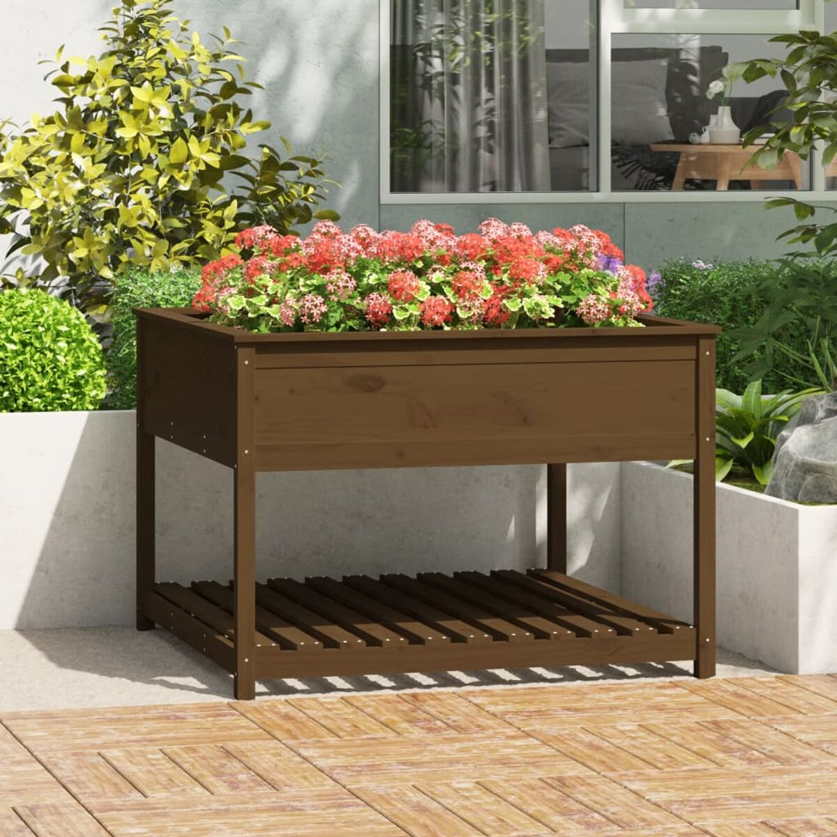 Ein brauner Holzpflanzer, gefüllt mit roten Blumen. Es steht in einem Garten.