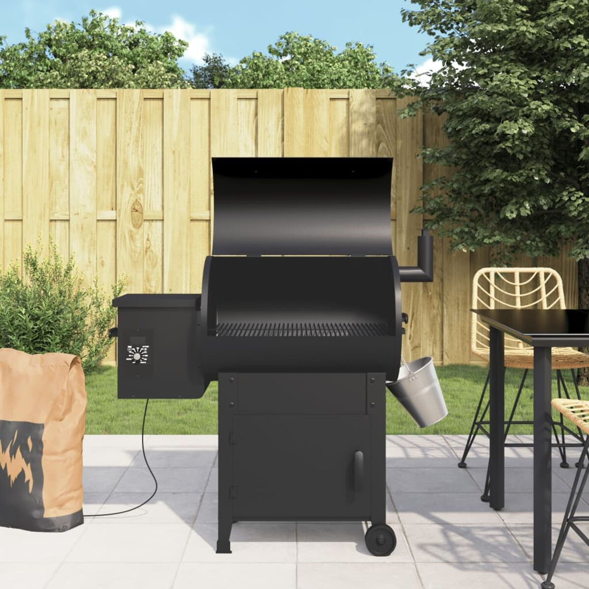 Schwarzer Grill auf einer Terrasse mit einem schwarzen Tisch und einer Holzkohletüte.