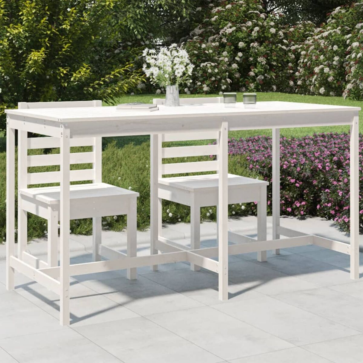 Weißes Ess-Set im Freien mit Tisch und zwei Stühlen auf einer Steinterrasse mit Garten im Hintergrund.