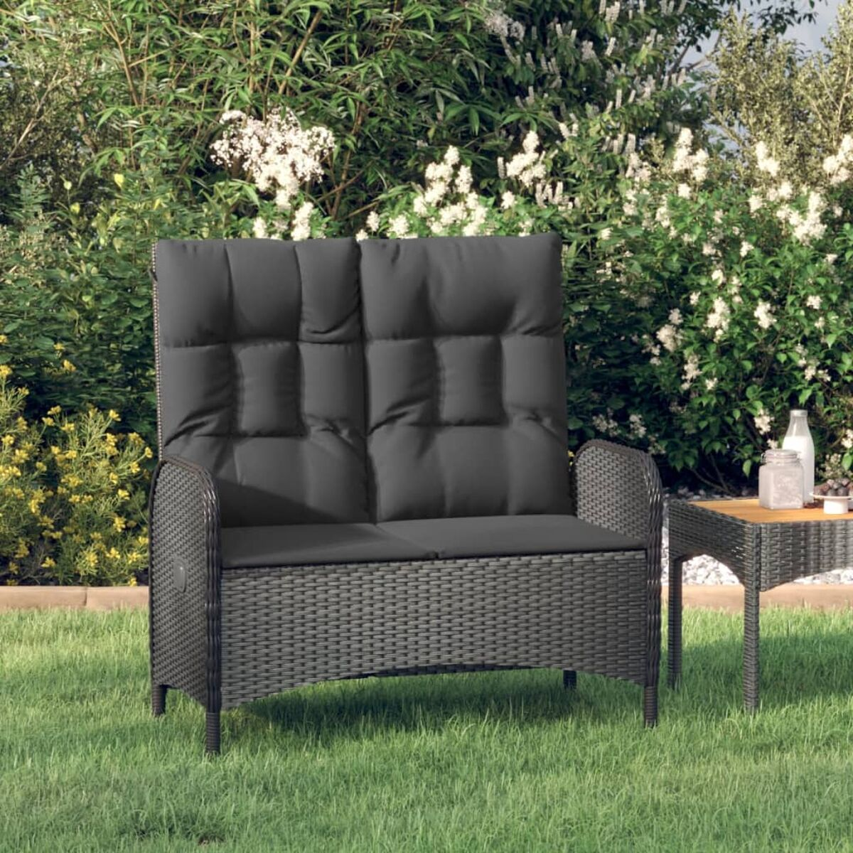 Dunkelgraues Outdoor-Sofa mit hohem Rücken, in einer Gartenszene.