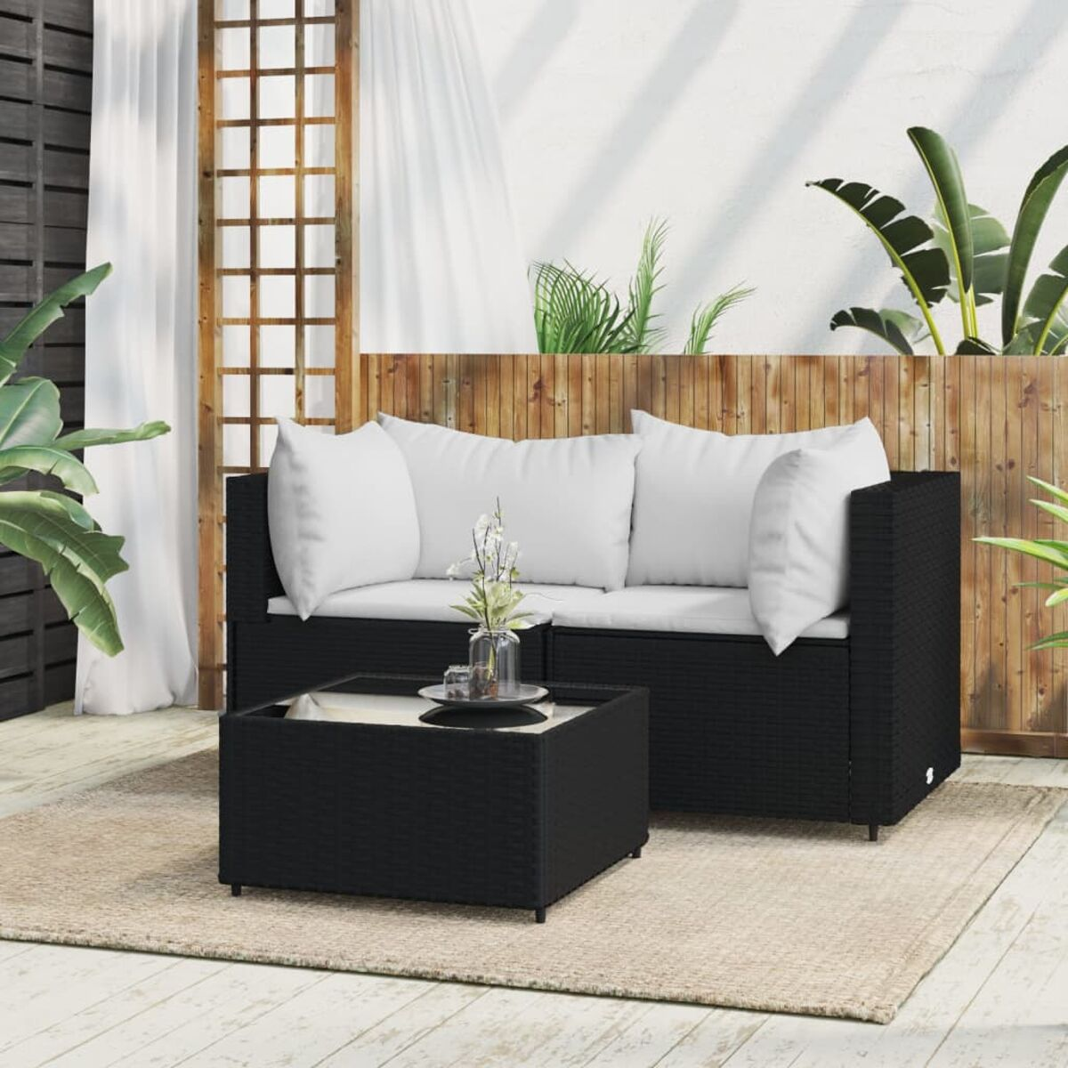 Ein schwarzes Outdoor-Möbelset aus Korbgeflecht mit weißen Kissen, auf Holz.